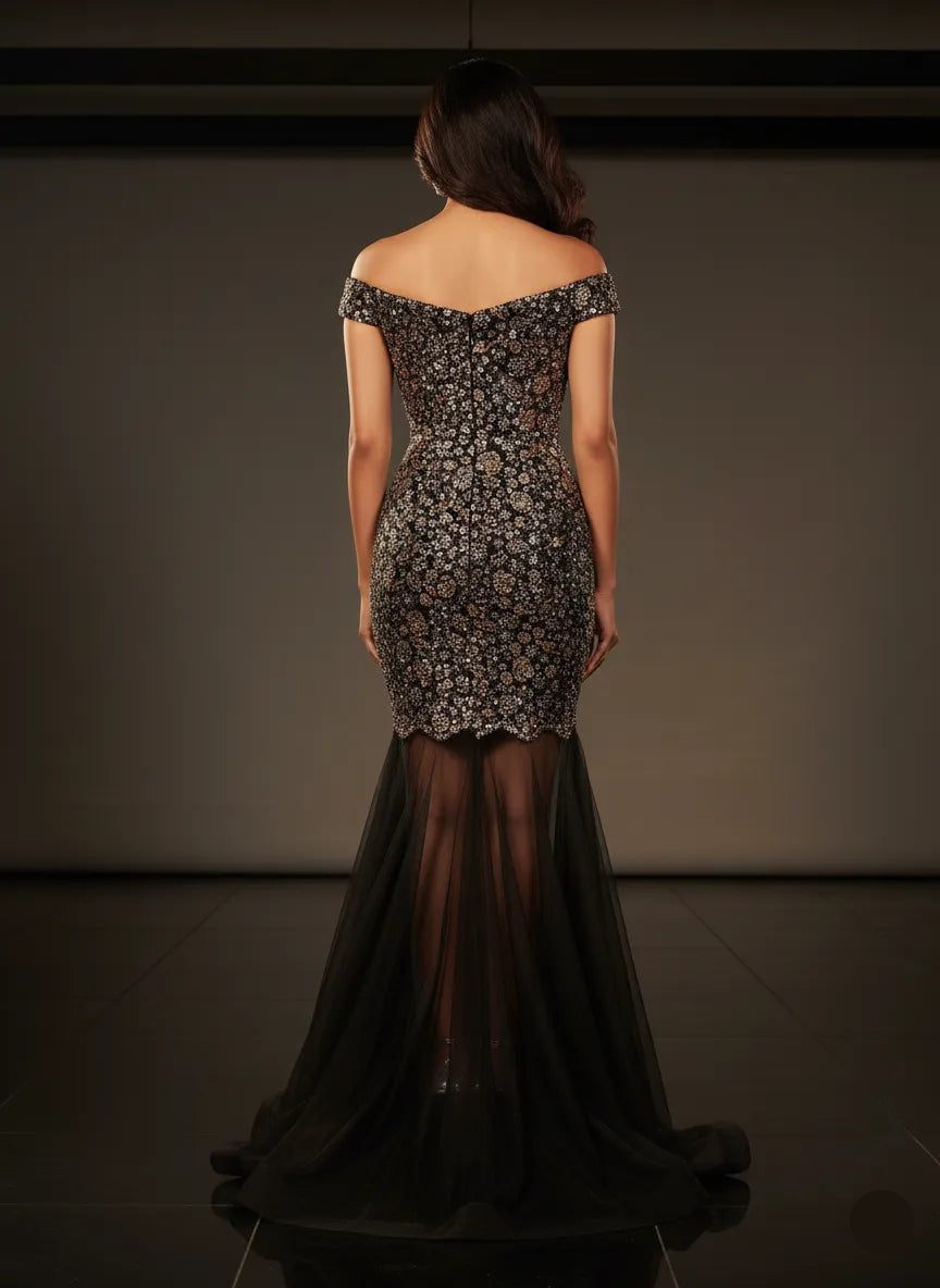 Woman wearing a dark, intricately designed evening gown against a plain background