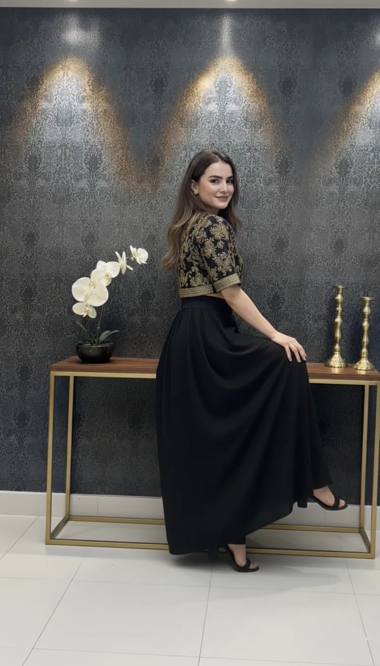 Woman in a black and gold outfit sitting on a bench against a decorative wall.