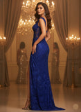 Woman in a blue evening gown standing in a grand room with chandeliers.