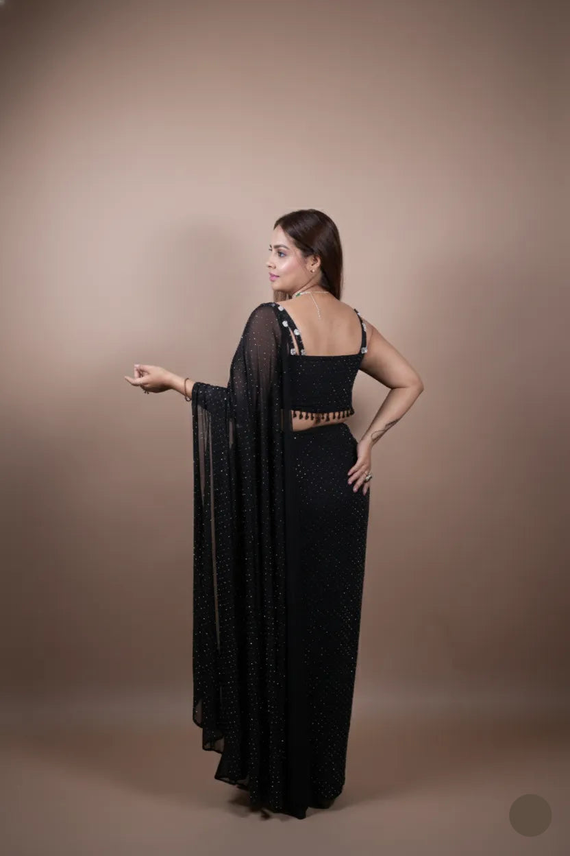 Woman wearing a black dress with sheer sleeves against a beige background