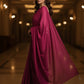 Woman in a magenta saree standing in an elegant indoor setting