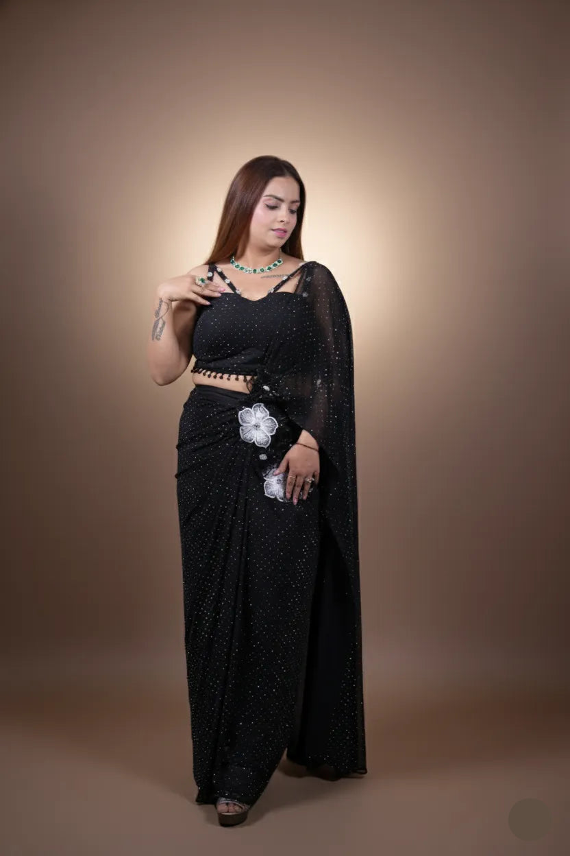 Woman wearing a black saree with white floral patterns on a brown background