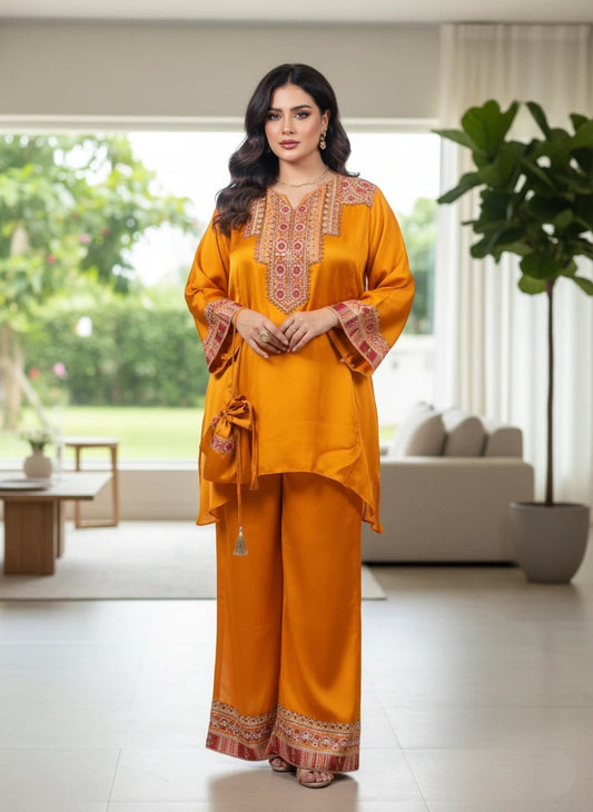 Woman in a mustard yellow traditional outfit with intricate patterns in a modern living room.
