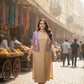 Woman in a beige dress with a purple jacket standing on a street market.