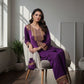 Woman in a purple traditional outfit sitting on a chair in a well-lit room.
