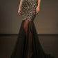 Black evening gown with gold floral pattern and sheer overlay on a dark background