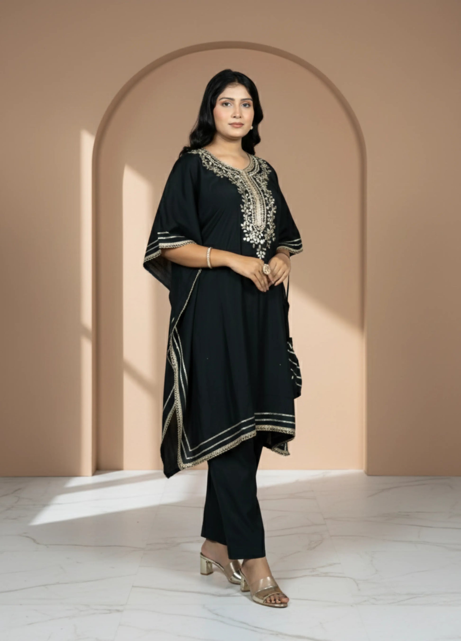 Woman wearing a black traditional outfit with embroidery in a beige archway.