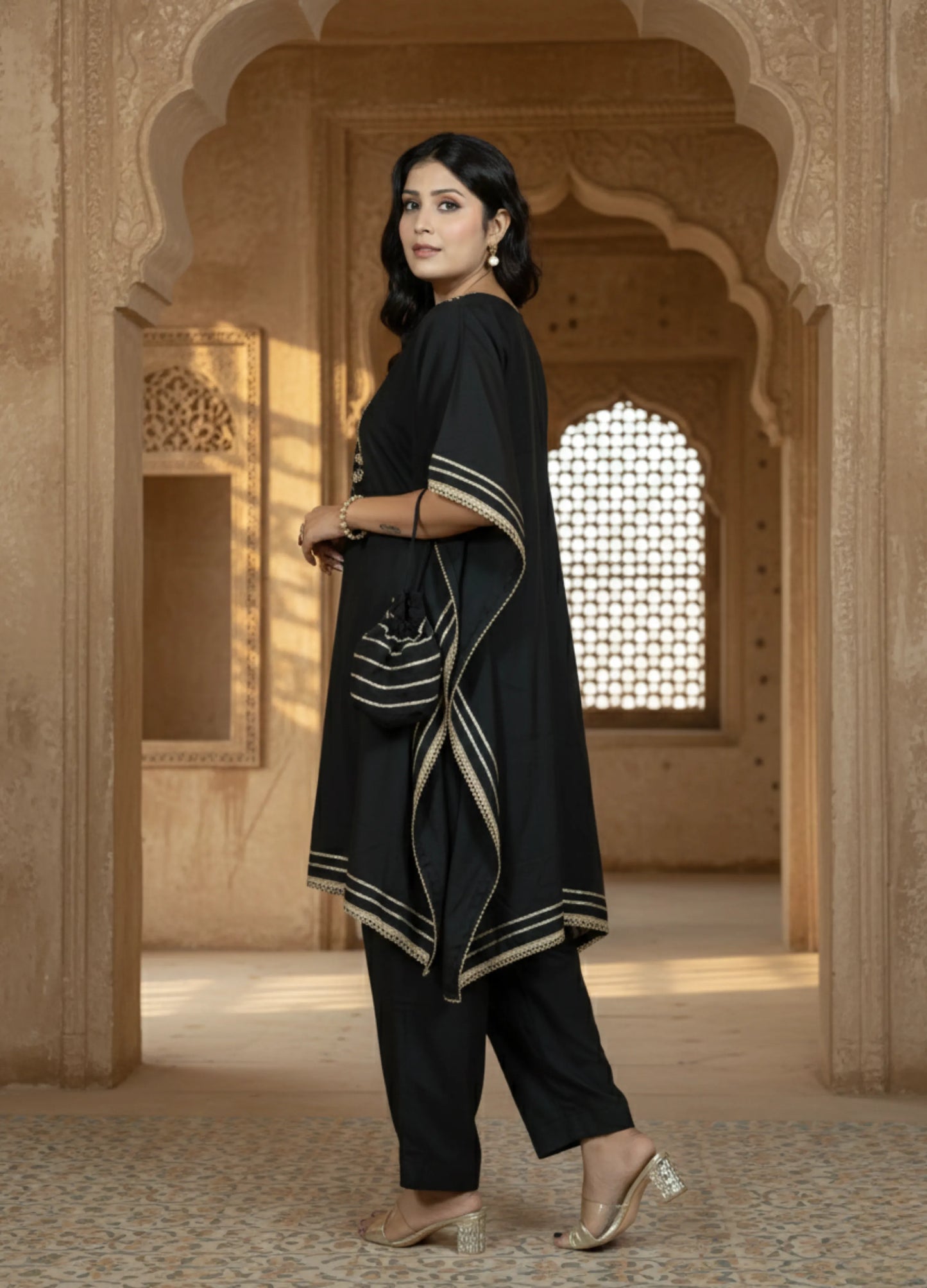 Woman in a black traditional outfit standing in an architectural setting