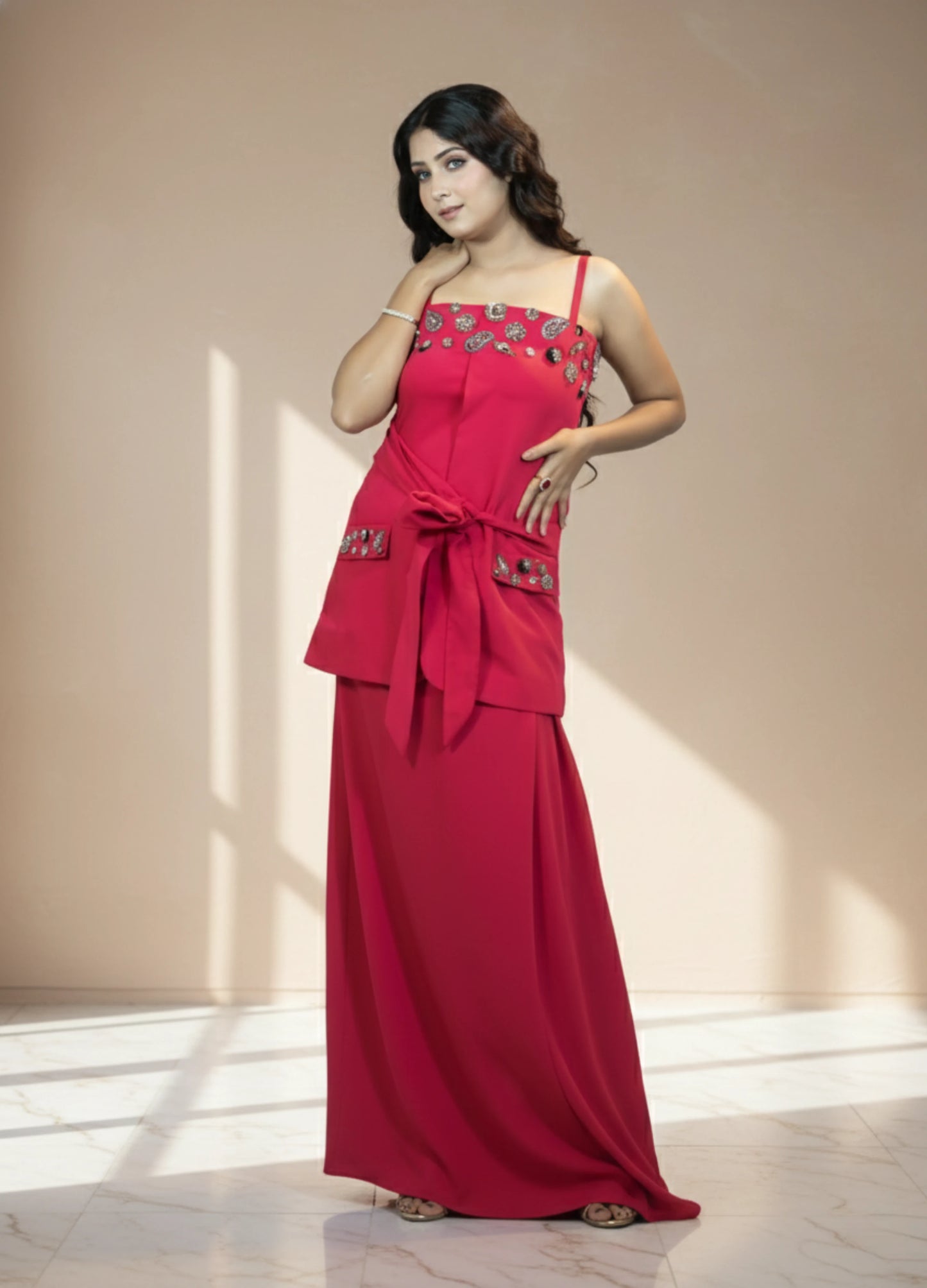 Woman wearing a red dress with floral embellishments in a well-lit room.