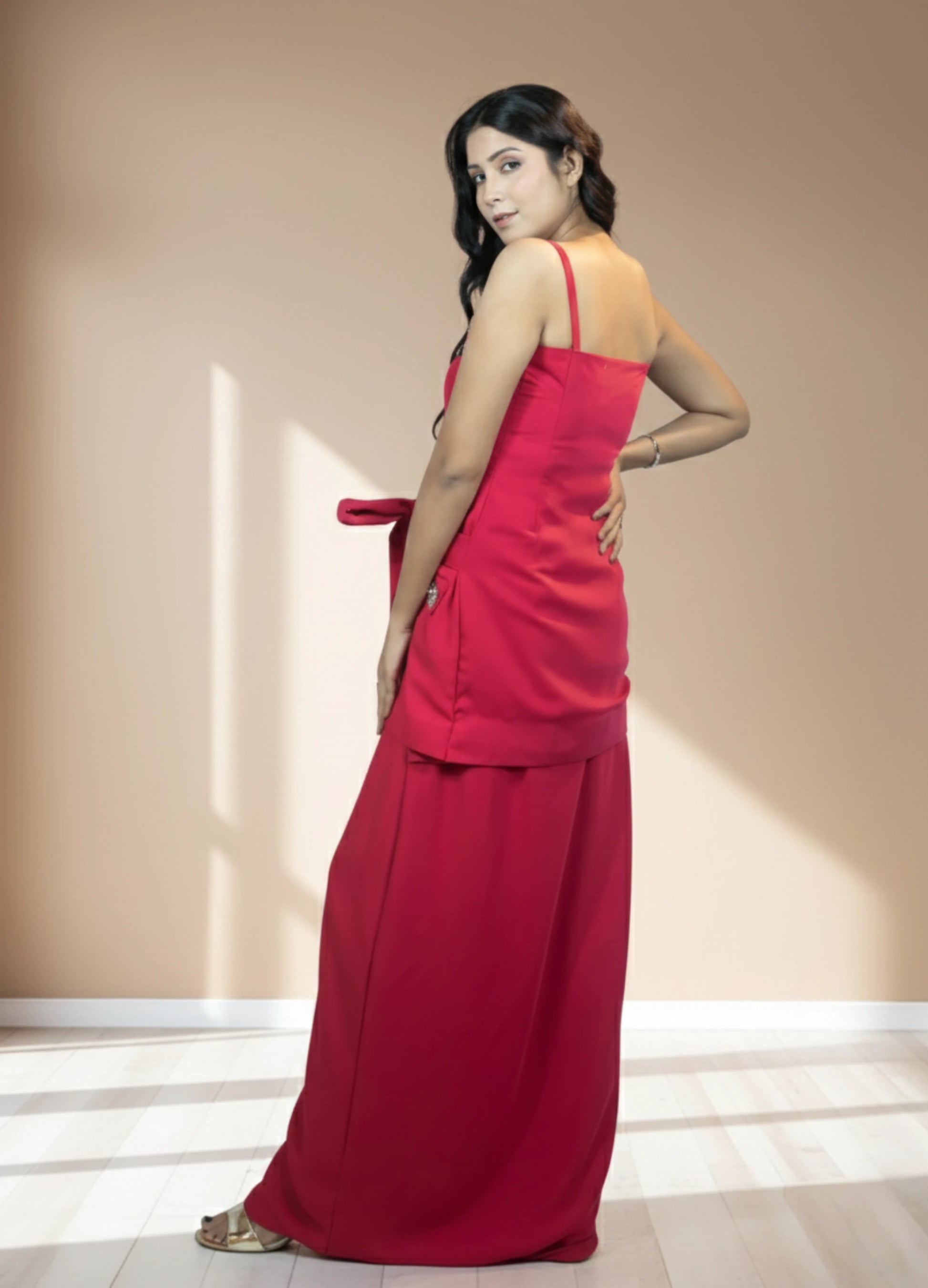 Woman wearing a red dress standing against a beige wall.
