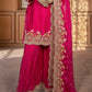 Pink traditional outfit with intricate embroidery on a wooden floor.