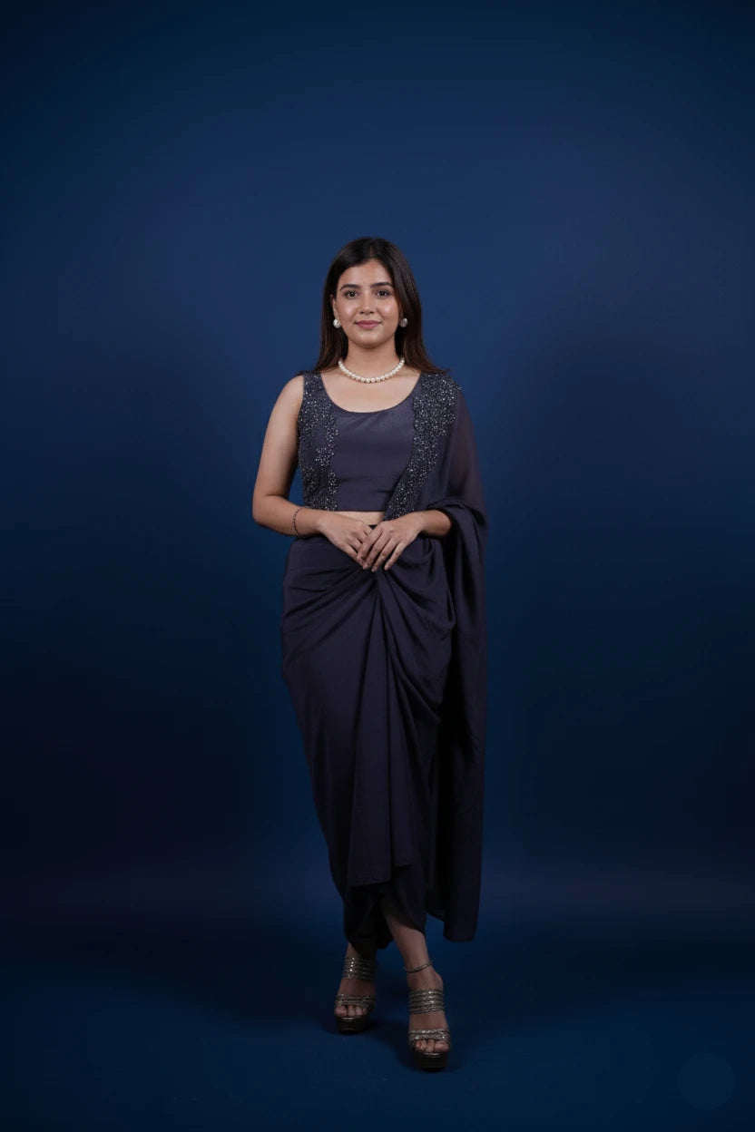 Woman in a dark purple saree standing against a blue background