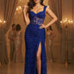 Woman in a blue evening gown standing in an elegant indoor setting with chandeliers.