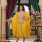 Woman in a yellow traditional outfit standing in an ornate room with decorative elements.