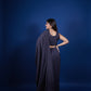Woman in a dark blue saree with a long train against a solid blue background