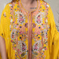 Yellow embroidered dress worn by a person, with intricate patterns and designs.