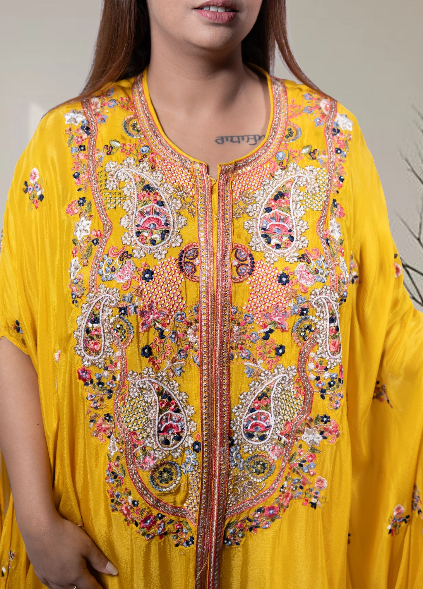 Yellow embroidered dress worn by a person, with intricate patterns and designs.