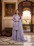 Woman in a lavender traditional outfit standing in an ornate room with decorative elements.