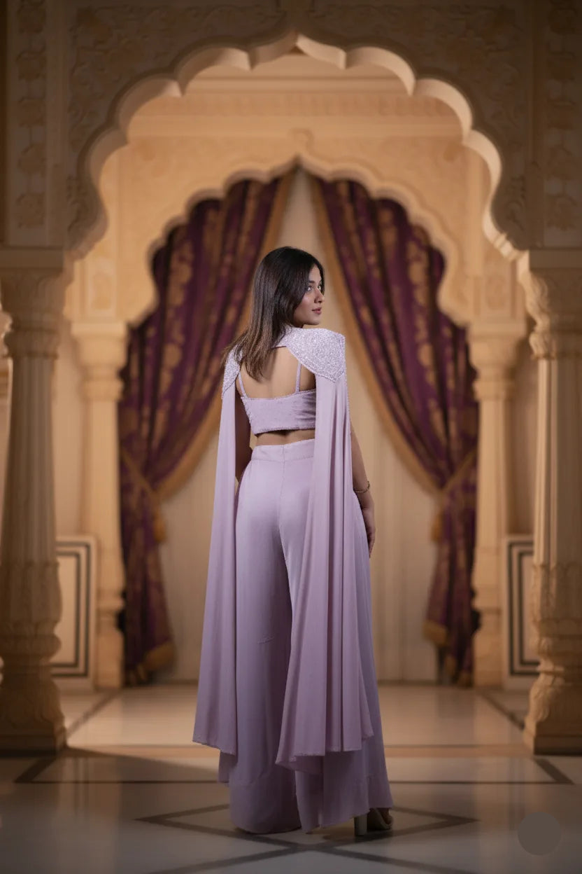 Woman in a lavender outfit standing in an ornate room with purple curtains.