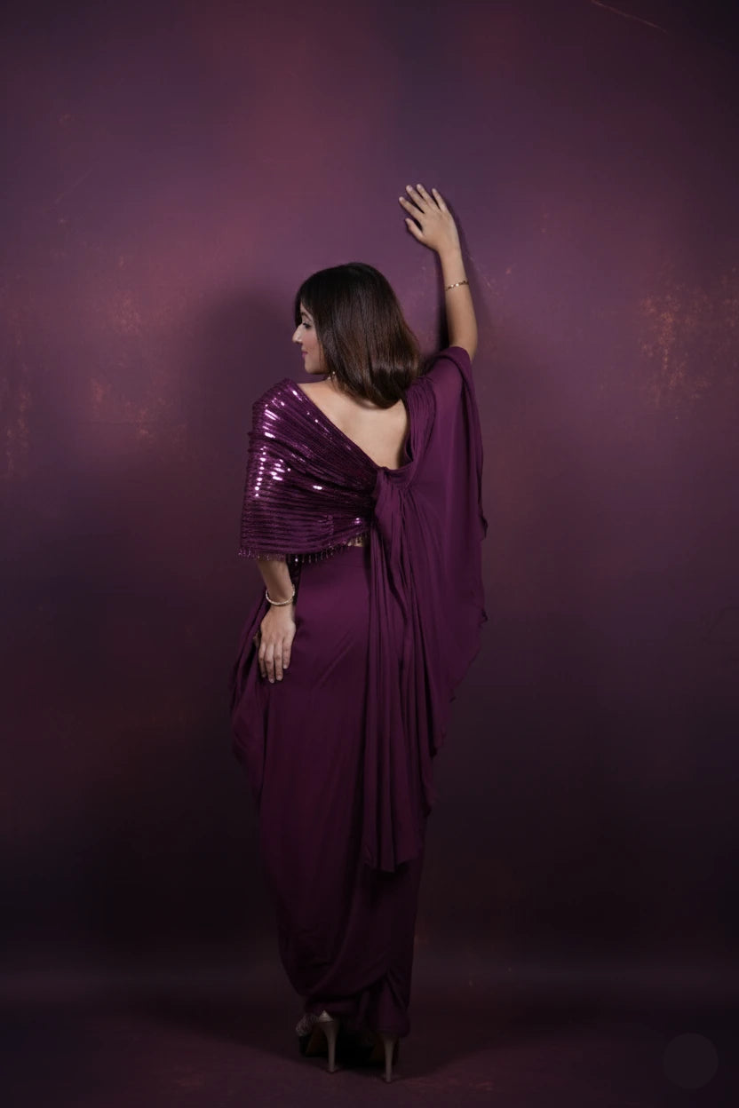 Woman in a purple saree posing against a dark purple background