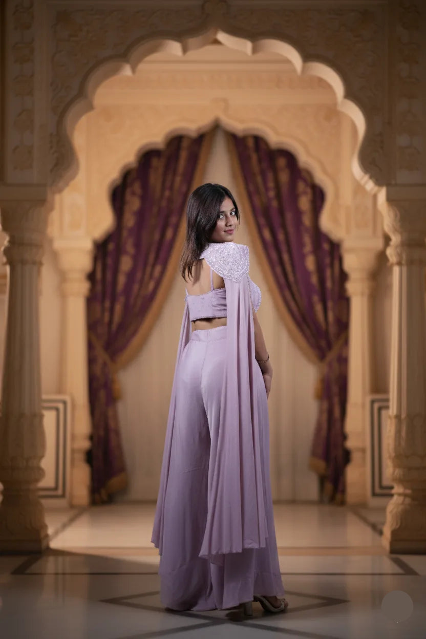 Woman in a lavender outfit standing in front of an ornate archway with purple drapes.