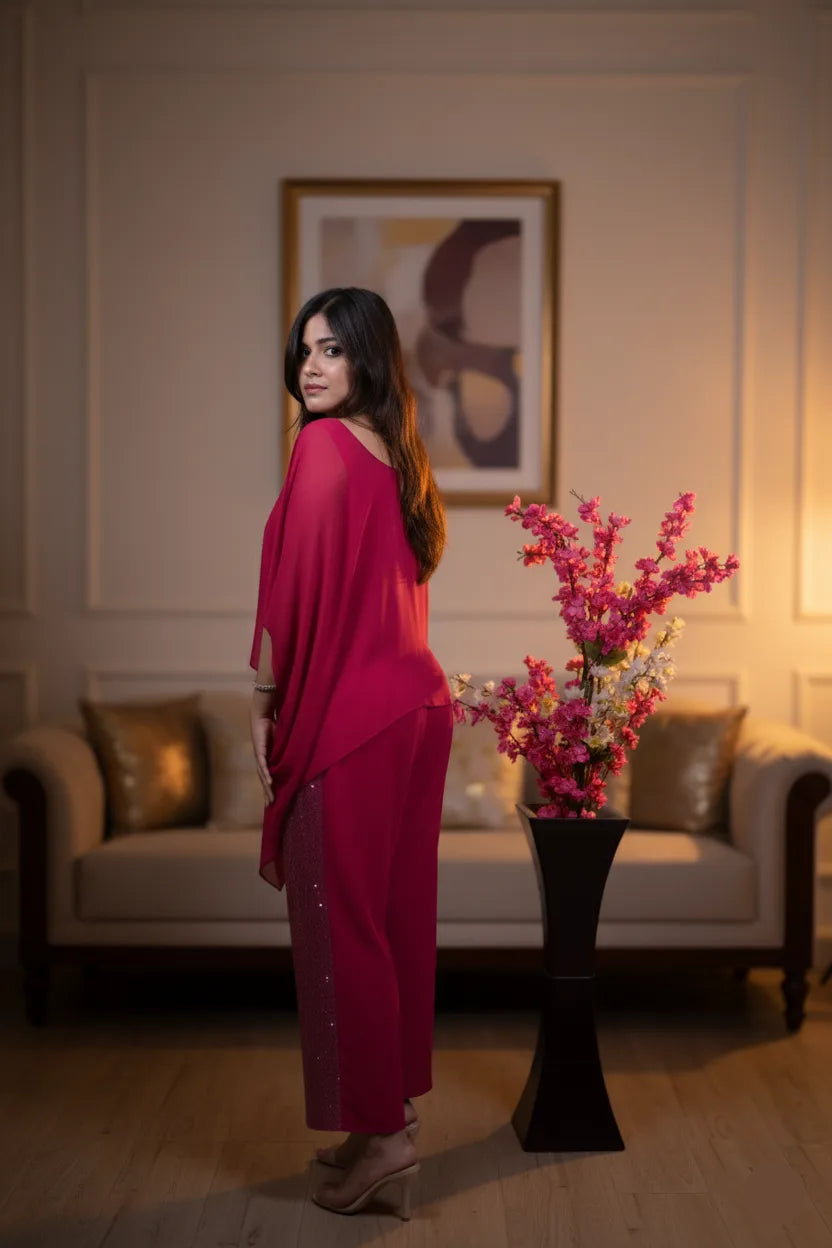 Woman in a pink outfit standing in a room with a vase of flowers and a couch.