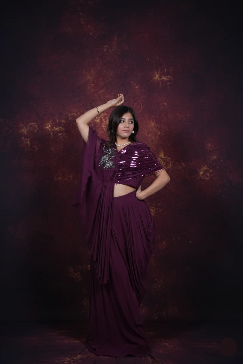 Woman in a purple saree against a dark background