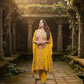 Woman in a yellow traditional outfit standing in an ancient temple setting
