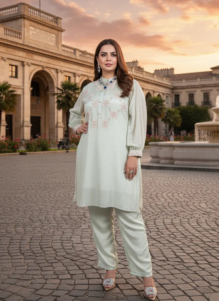 Woman in a light green traditional outfit standing in front of an architectural building with a fountain at sunset.