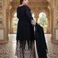 Woman in black traditional outfit with intricate patterns in a ornate indoor setting